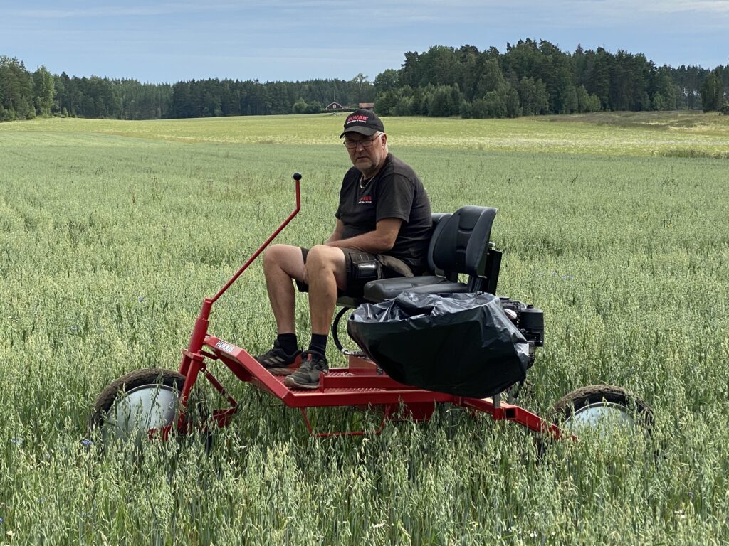 En bild på en bonde som sitter på HUKKIS, tillsammans med en påse att sätta flyghavren i.